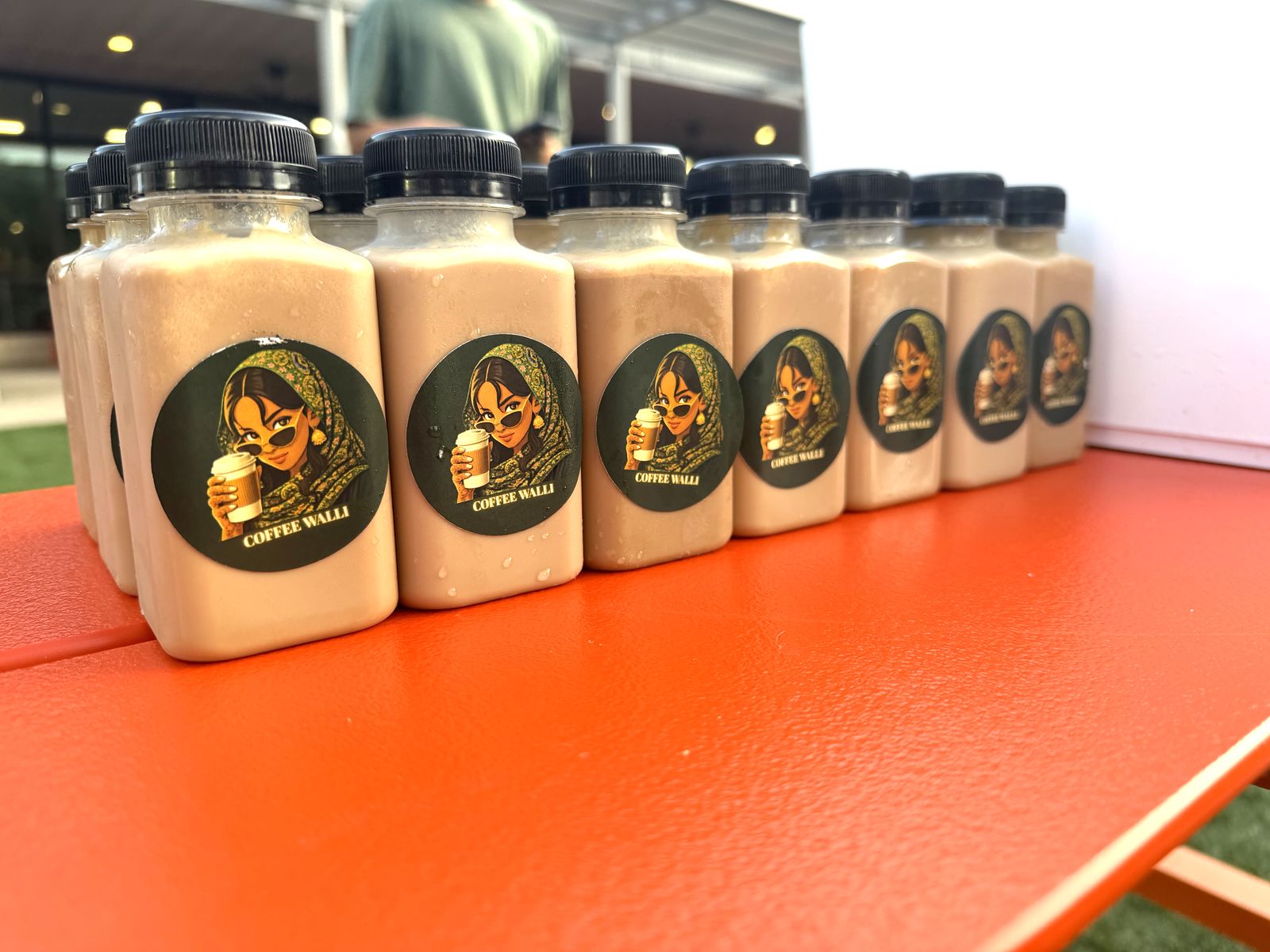 Bottled Coffee Walli drinks with the mascot sticker lined up on an orange picnic table