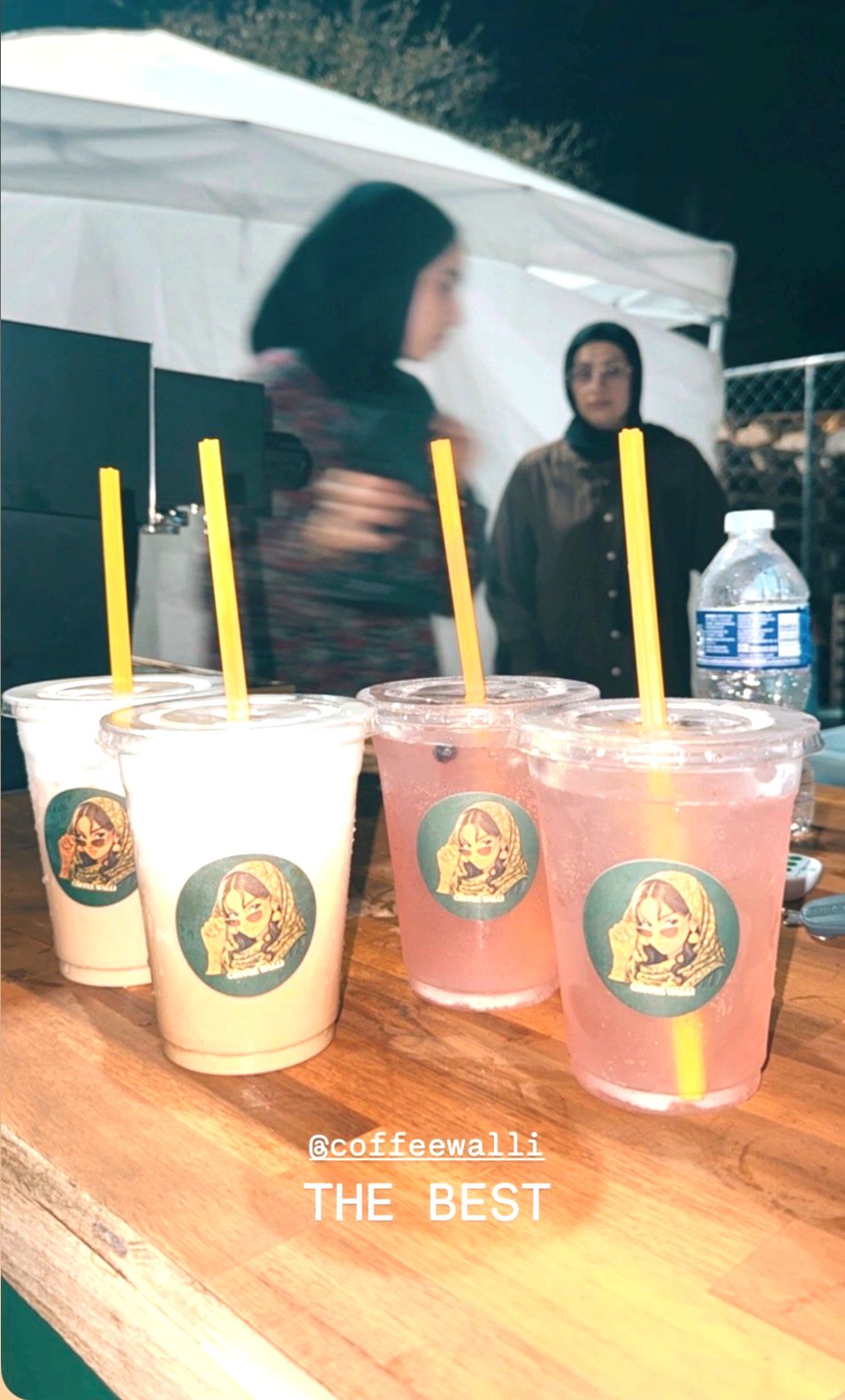 Four drinks lined up on the stand's wooden counter at a night market